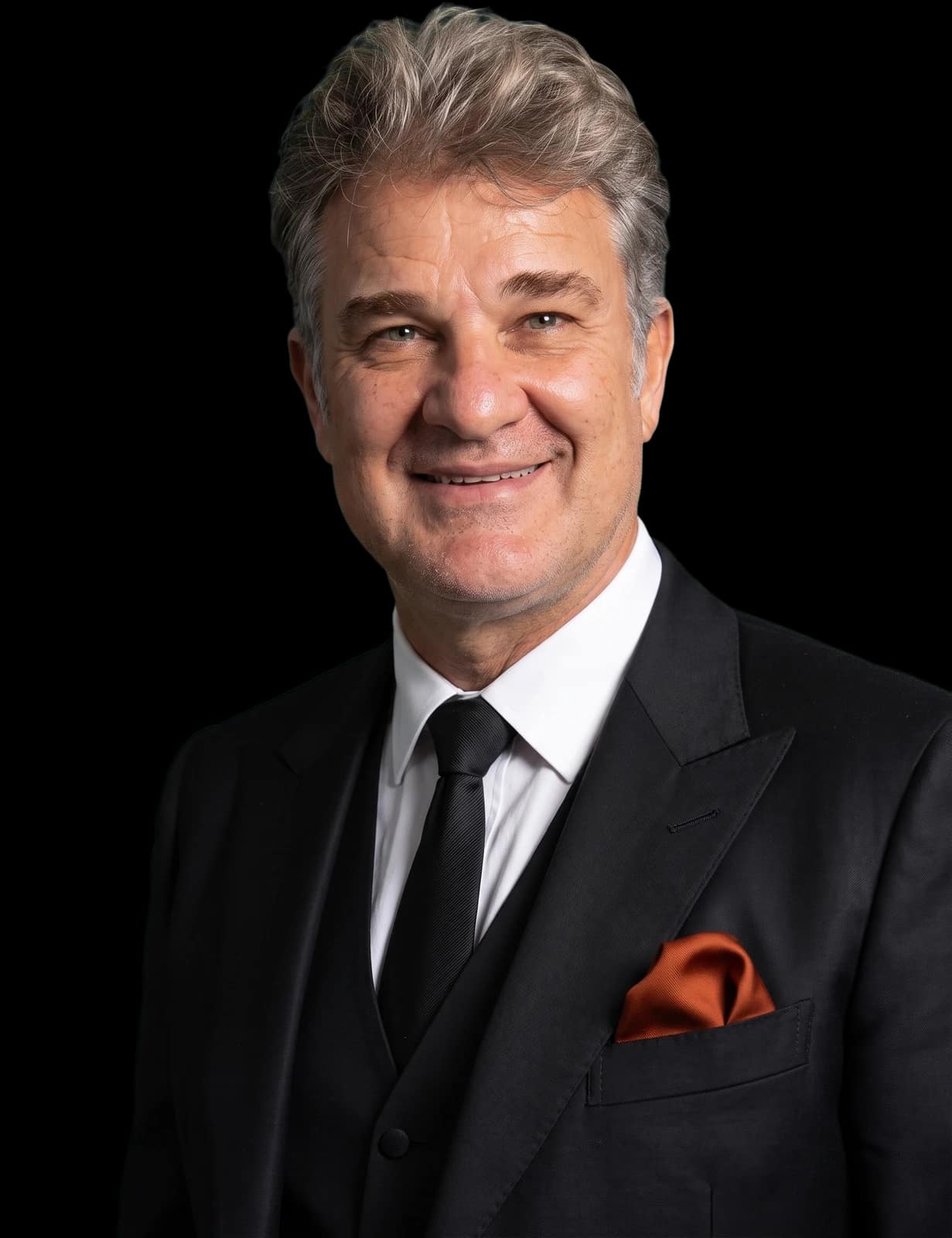 Daniel Santos Cori in a black three-piece suit with a burnt-orange pocket square
